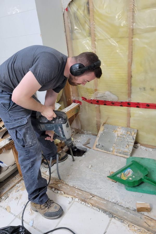 A man doing renovation work in a bathroom.