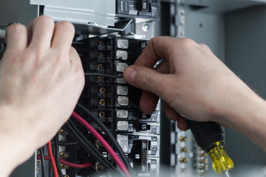 Two hands working on an electrical panel