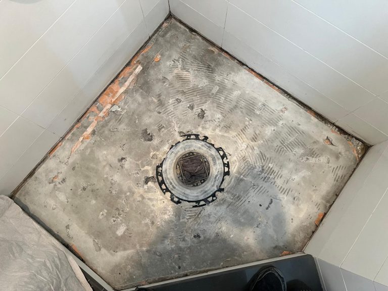 A shower renovation in progress, with the old floor tile removed.