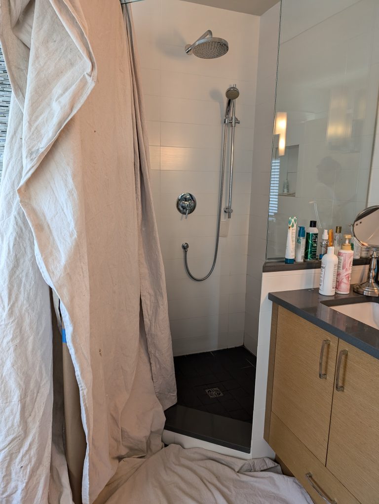 A bathroom renovation in progress with a tarp covering part of the shower.